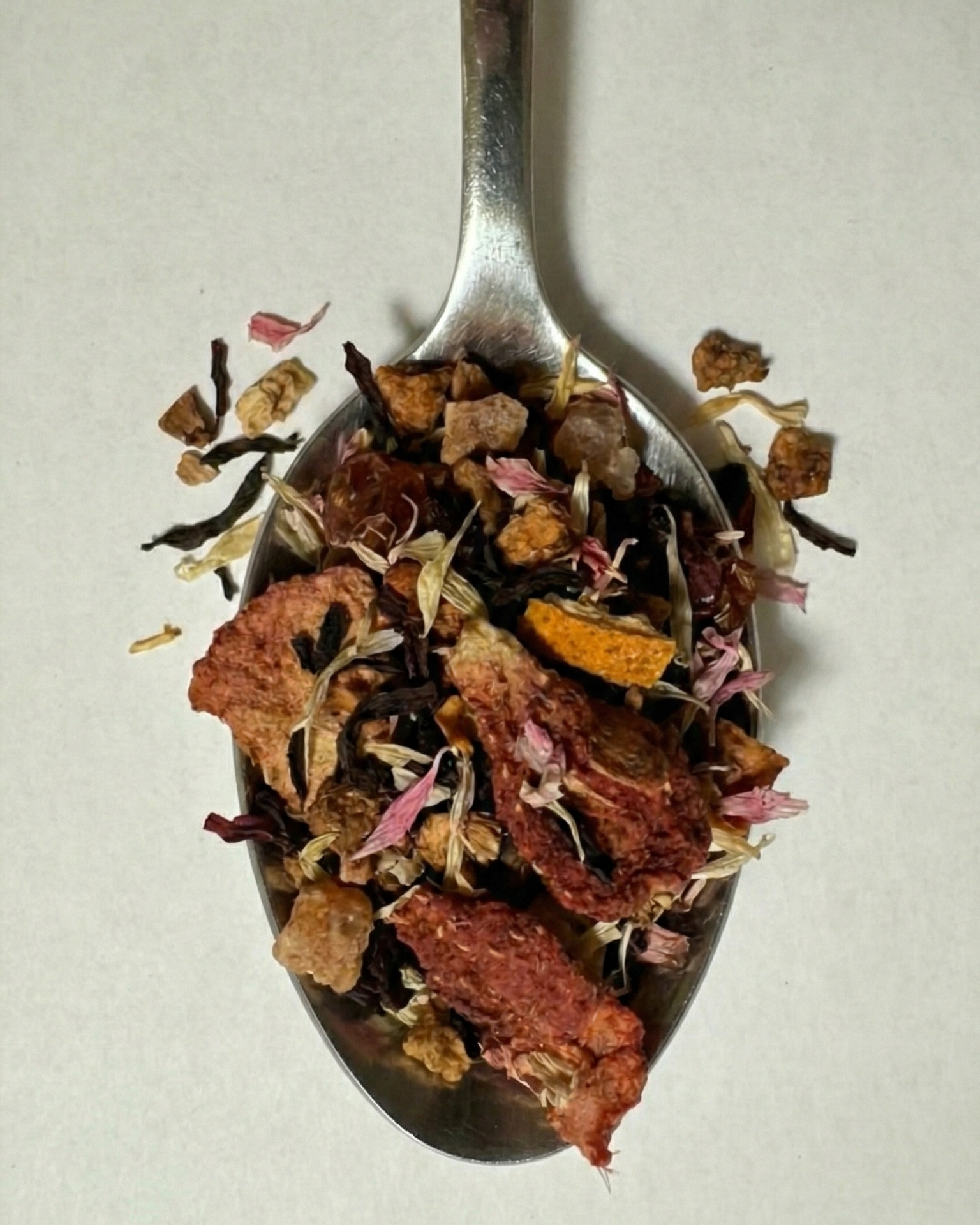 Tea leaves on a silver spoon against a neutral background