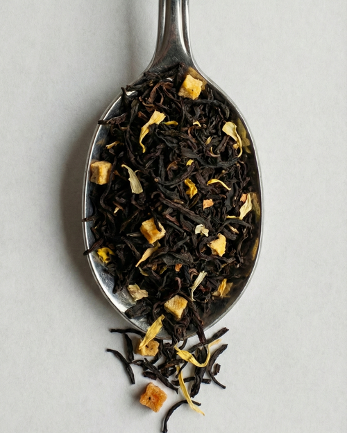 Tea leaves on a silver spoon against a light gray background