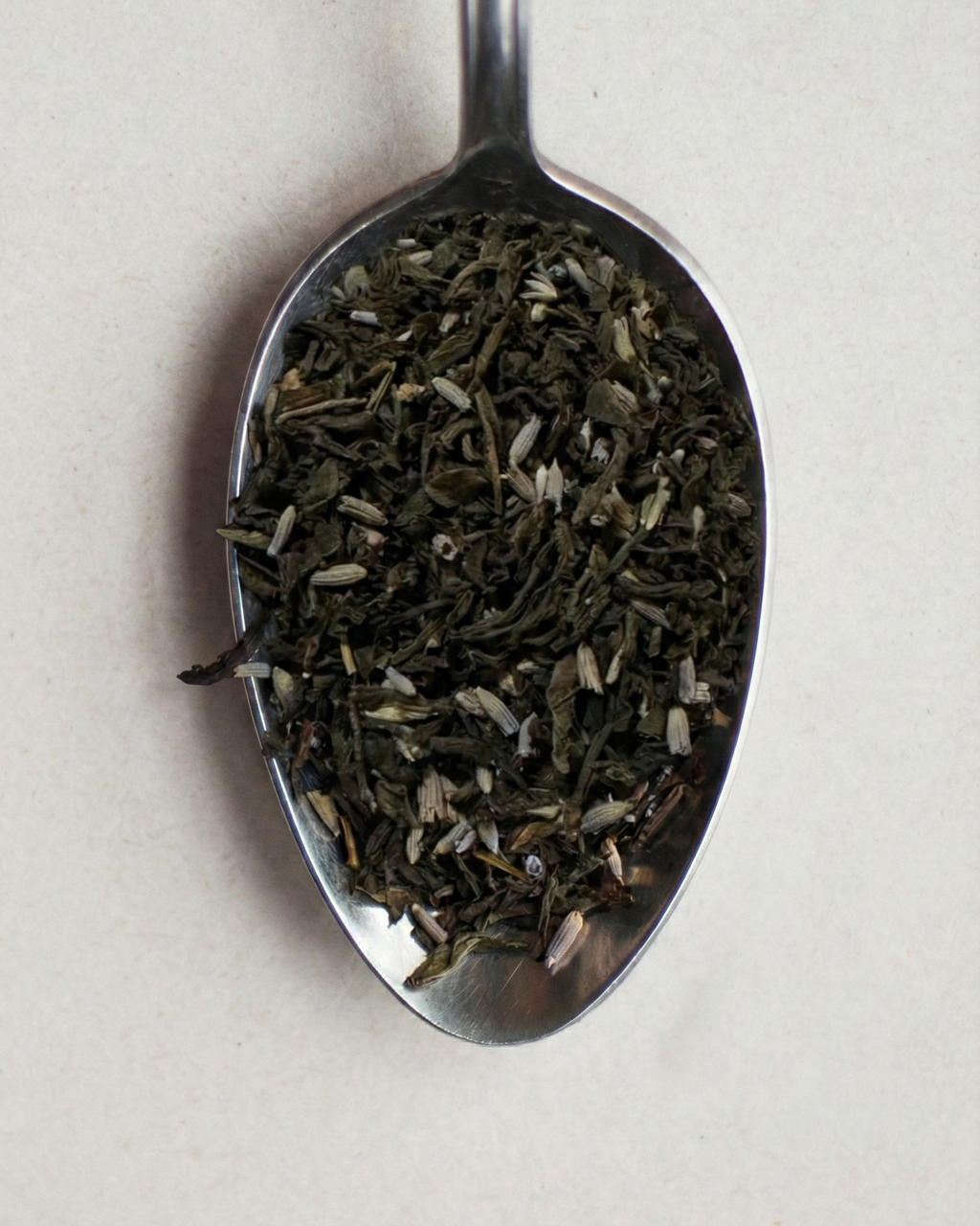 Tea leaves on a metal spoon against a light background