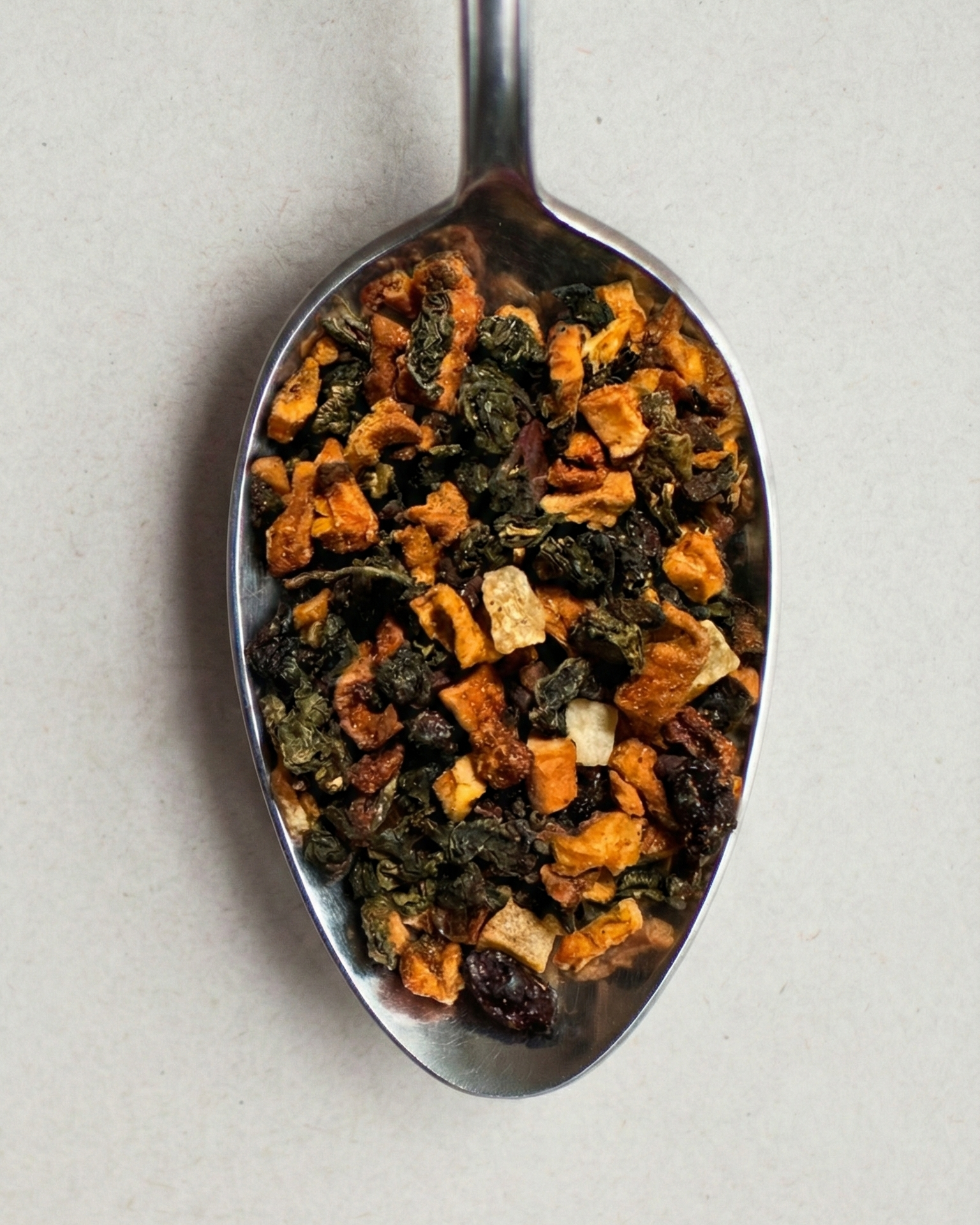 Tea leaves on a metal spoon against a light background