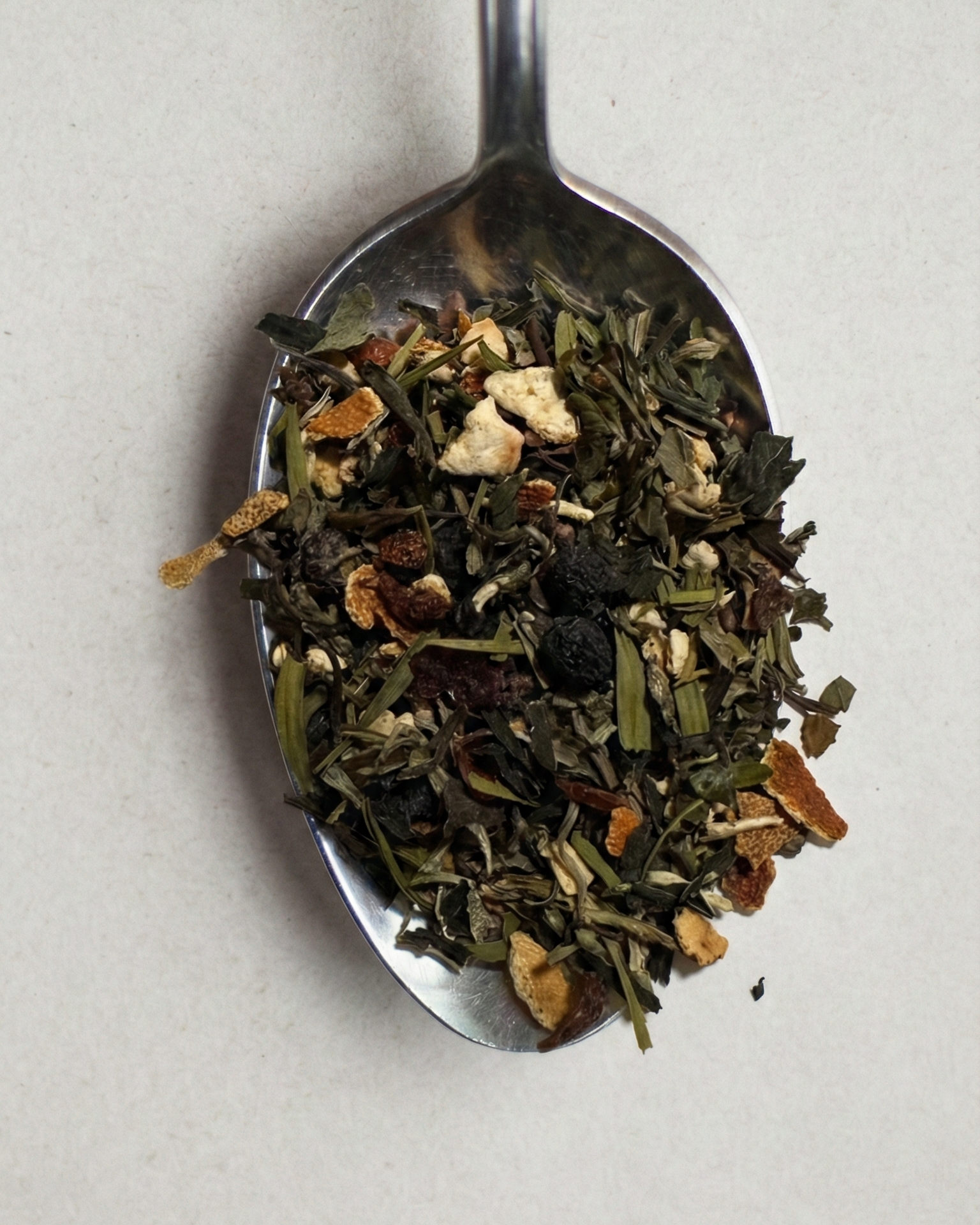 Tea leaves on a metal spoon against a light background