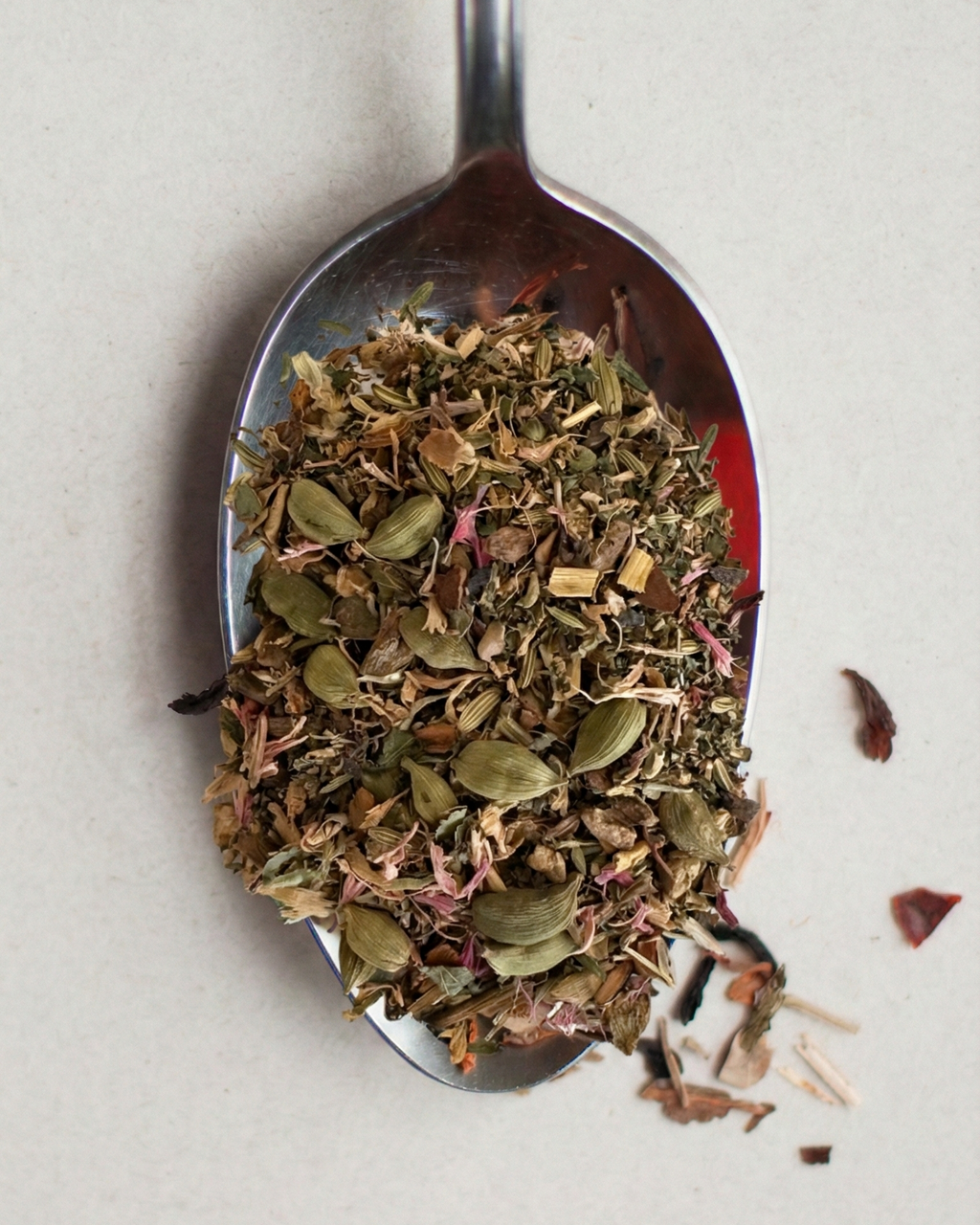 Tea leaves on a metal spoon against a light background